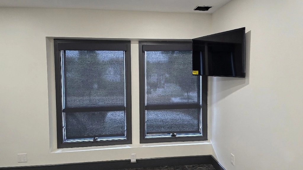 Custom solar roller shades with fabric-wrapped cornices installed in a commercial office corner room